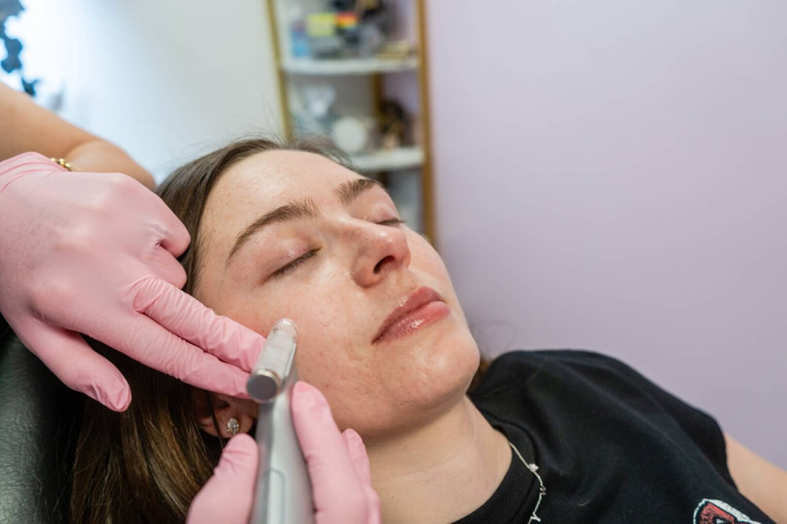 A woman getting her face shaved by a person.