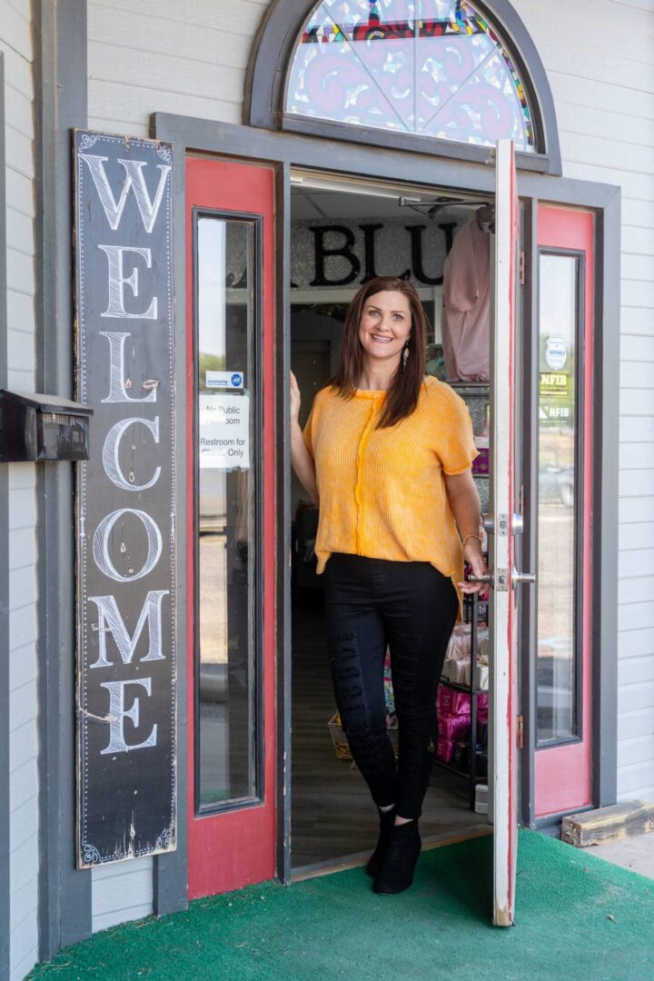 A woman standing in front of a store entrance.