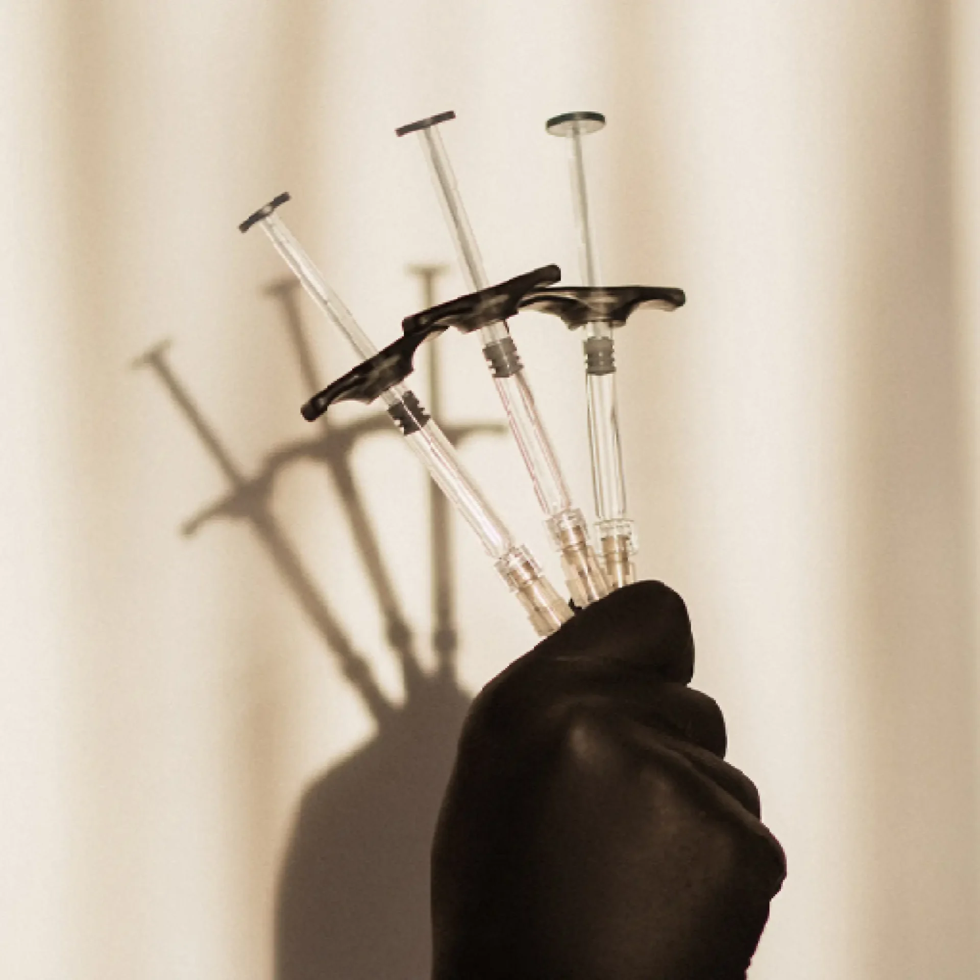 A hand holding six needles in front of a curtain.